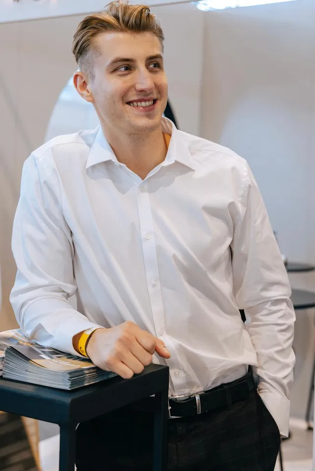 Sebastian Kostrzewa uśmiechnięty na branżowym evencie, w białej koszuli